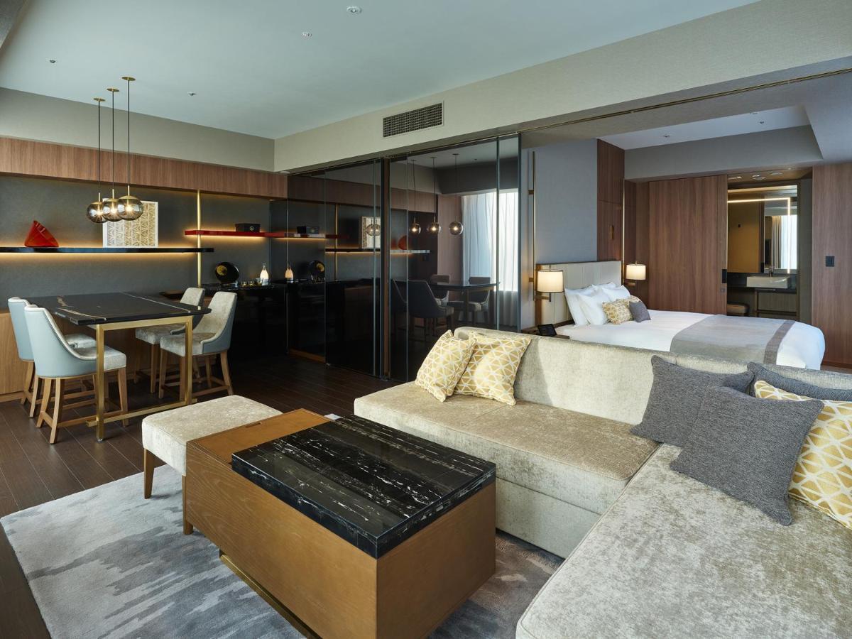 Mitsui Garden Hotel Roppongi Tokyo Premier Eksteriør billede The image shows a modern hotel room or suite that features a contemporary design. Key elements include:

- A comfortable seating area with a light-colored sofa and a stylish coffee table.
- A dining area with a table and chairs, suggesting space for 