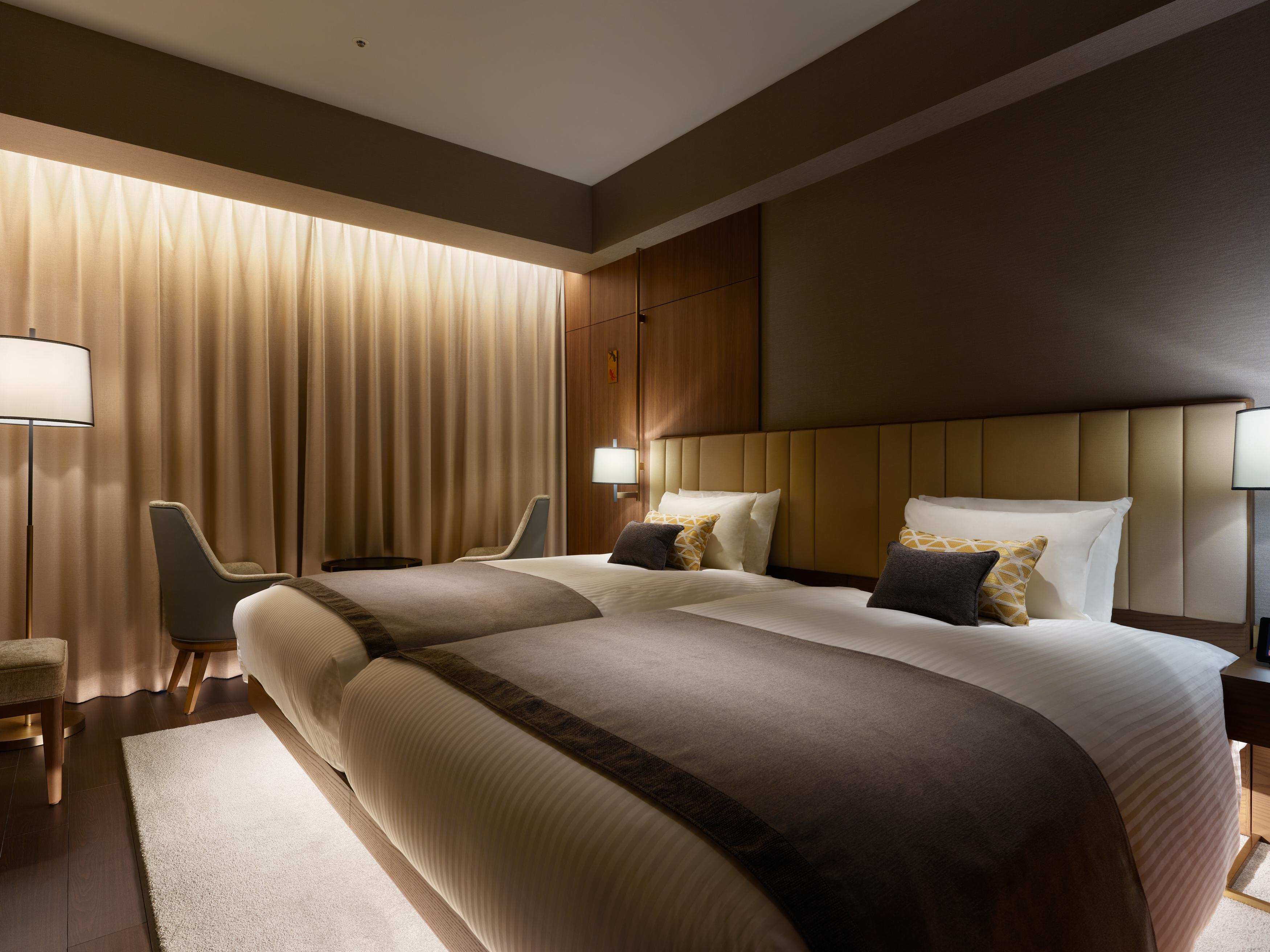 Mitsui Garden Hotel Roppongi Tokyo Premier Eksteriør billede The photo shows a modern hotel room featuring two twin beds with elegant bedding. The room is adorned with soft, neutral tones and has a warm ambiance created by subtle lighting. A pair of bedside lamps provide additional light, and there is a cozy c