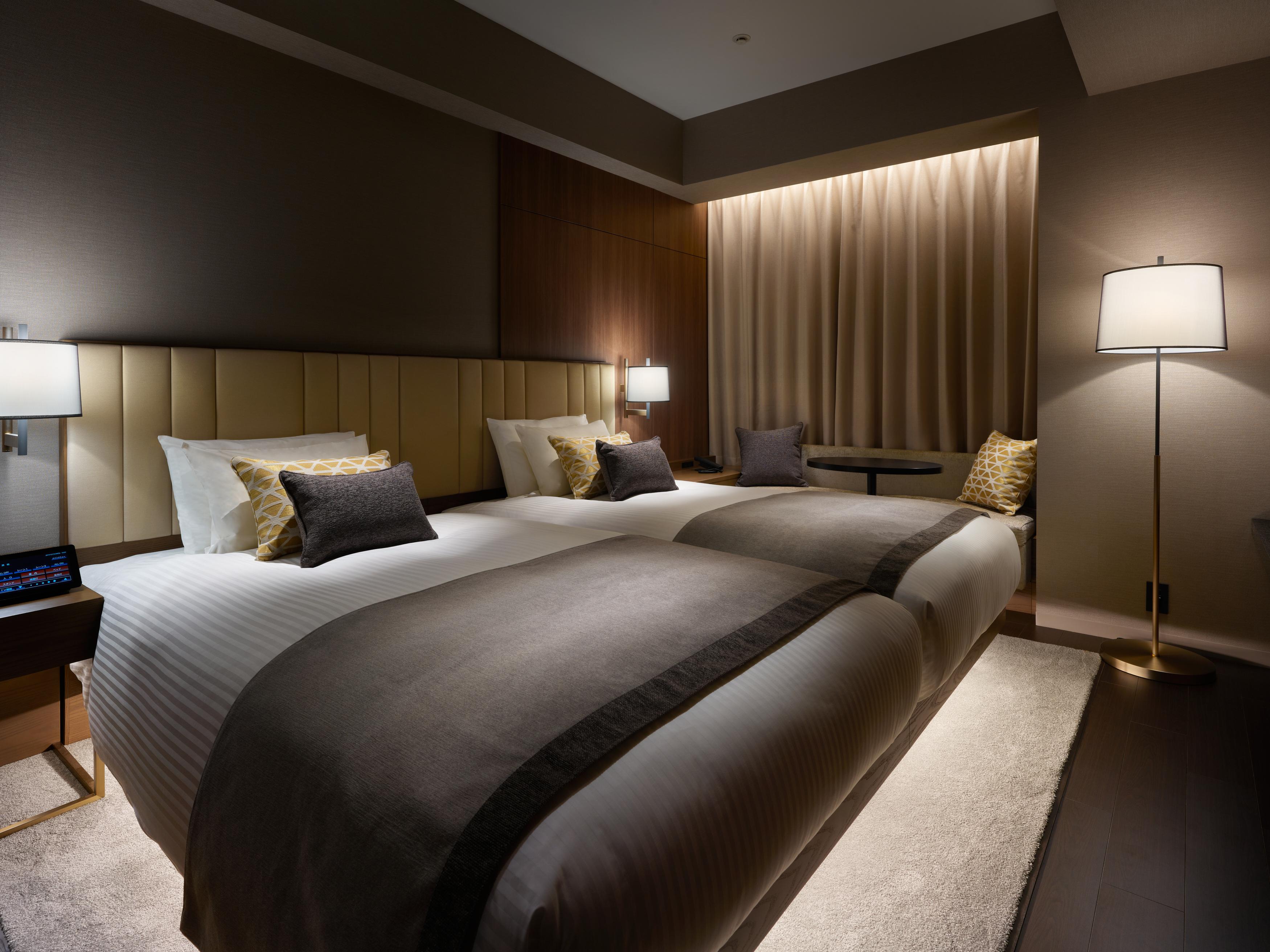 Mitsui Garden Hotel Roppongi Tokyo Premier Eksteriør billede The photo shows a modern hotel room featuring two beds with elegant bedding in neutral colors. Each bed is adorned with decorative pillows. The room has a sophisticated ambiance with dim lighting, highlighted by table lamps on either side of the beds