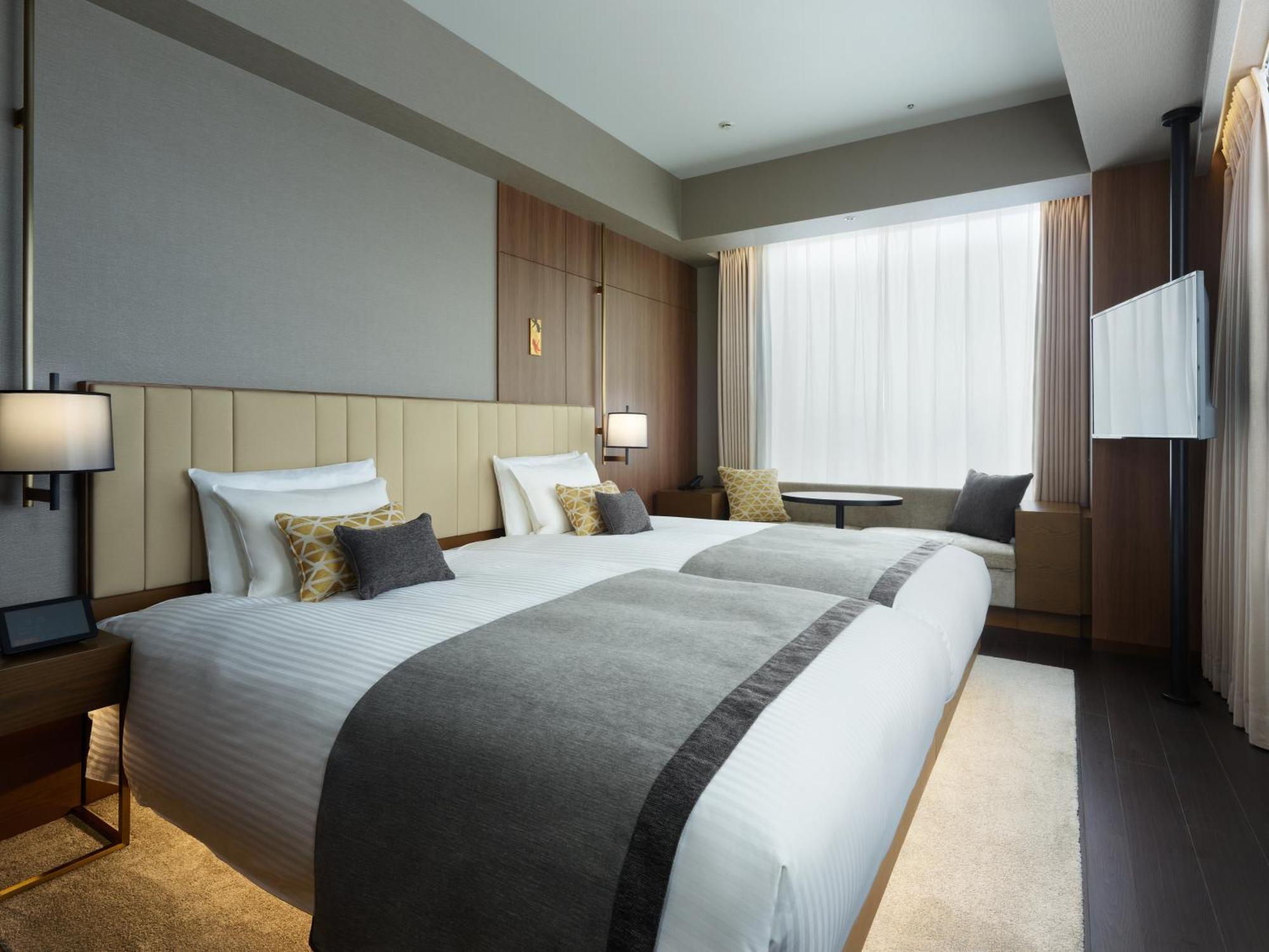 Mitsui Garden Hotel Roppongi Tokyo Premier Eksteriør billede The photo shows a modern hotel room featuring two beds with white linens and decorative pillows. The room has a minimalist design, with neutral-colored walls and wooden accents. Natural light comes in through large windows, which are partially covere